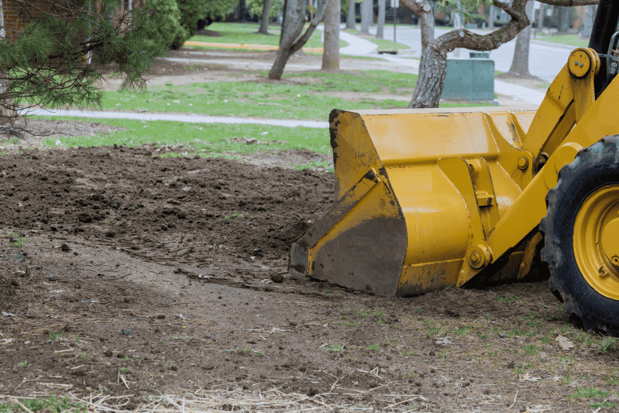 yellow construction machine picking up some dirt